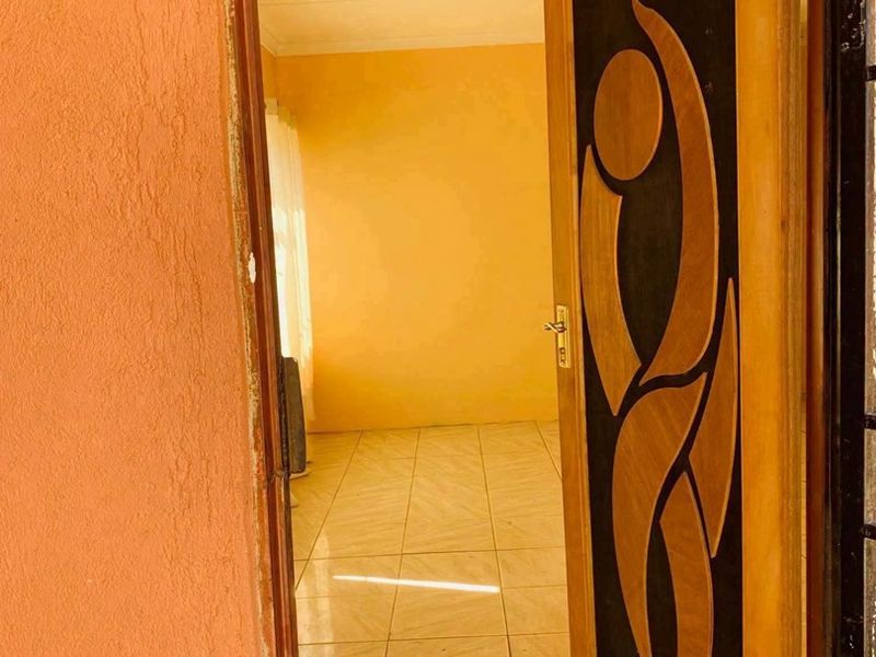 An entryway featuring a decorative wooden door leading into a tiled, vacant room with yellow walls.