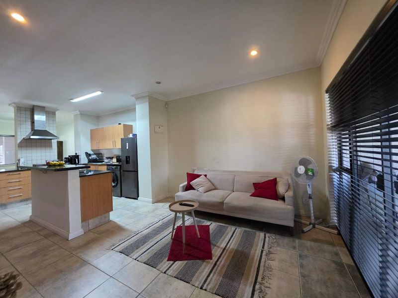 Open-plan living area featuring a functional kitchen with granite countertops, stainless steel extractor fan, and tiled flooring throughout.