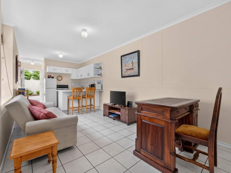 Open-plan living area featuring tiled flooring, a compact kitchen with built-in cabinetry, and direct access to an outdoor space.