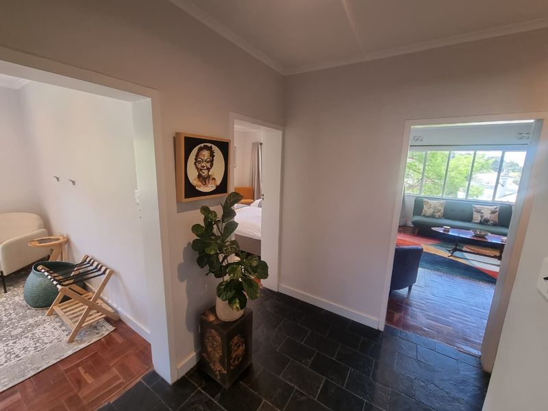 A central hallway featuring a transition between slate tile and parquet flooring, providing access to multiple rooms within the apartment.