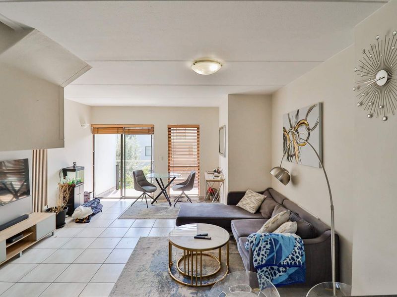 Open plan living and dining area featuring tiled flooring, neutral walls, and a sliding glass door leading to a balcony.