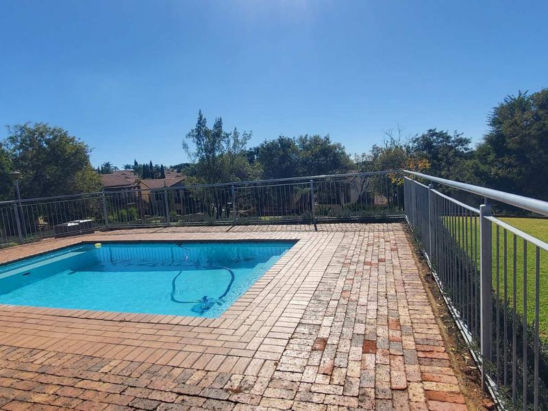 Outdoor pool area featuring a swimming pool surrounded by brick paving and secured with metal safety railings.