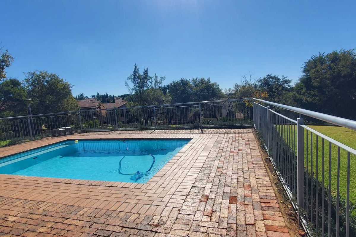 Outdoor pool area featuring a swimming pool surrounded by brick paving and secured with metal safety railings.