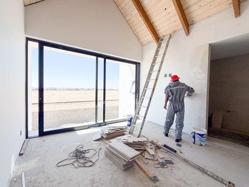 An unfinished living area featuring a high vaulted timber ceiling with exposed beams and large sliding glass doors leading to an outdoor view.