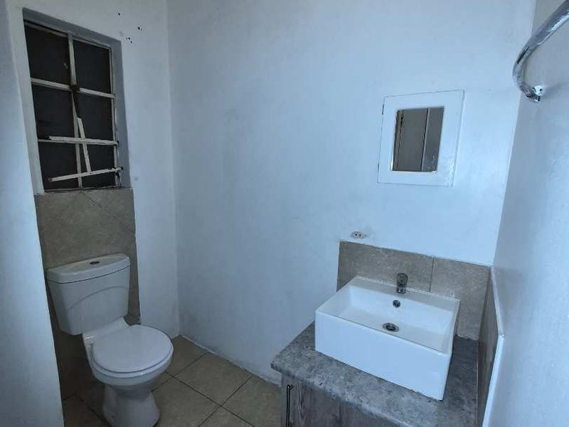 A compact bathroom featuring a modern vessel sink on a vanity cabinet, a standard toilet, and tiled flooring.