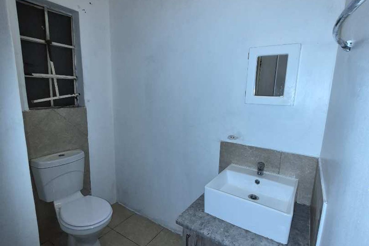 A compact bathroom featuring a modern vessel sink on a vanity cabinet, a standard toilet, and tiled flooring.