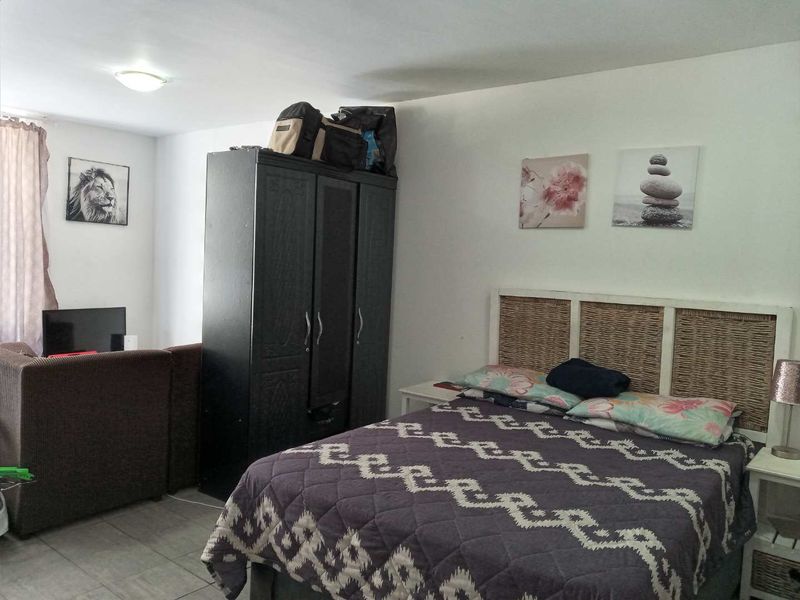 A functional bedroom featuring tiled flooring and neutral wall finishes, providing a practical living space.