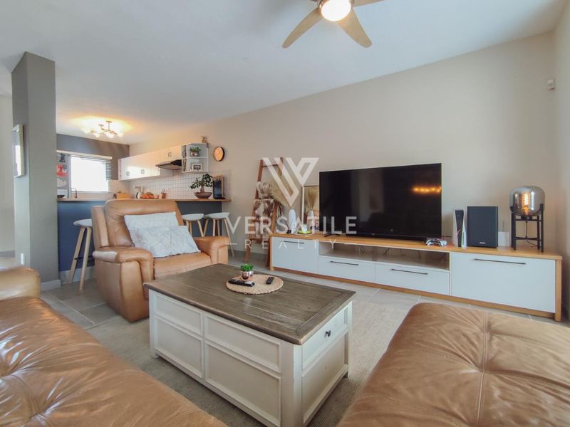 Open plan living area featuring tiled flooring, a ceiling fan, and a functional kitchen with a breakfast bar.