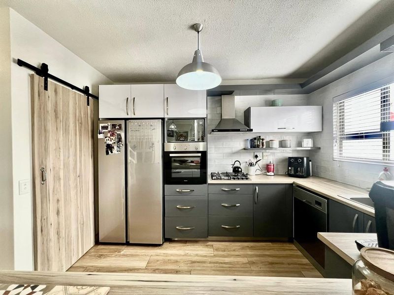 Modern kitchen featuring dark grey cabinetry, light wood-look countertops, subway tile backsplash, and high-quality built-in appliances including a gas hob and oven.