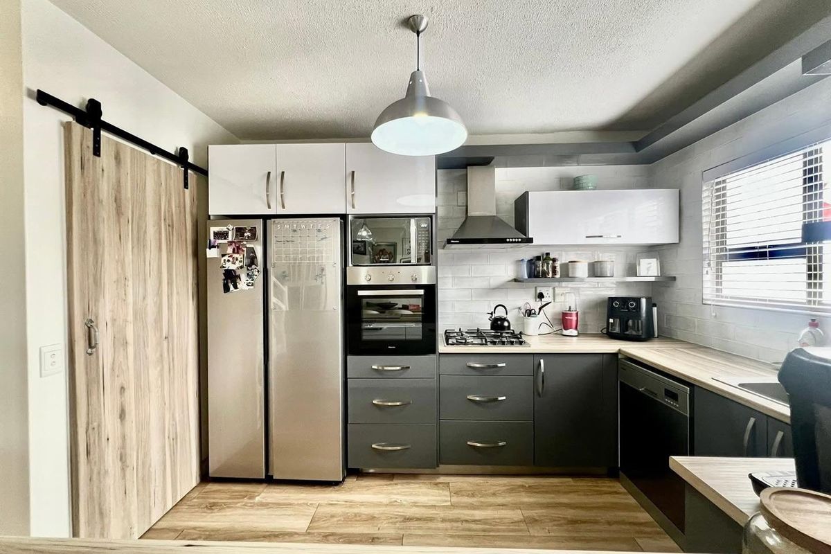 Modern kitchen featuring dark grey cabinetry, light wood-look countertops, subway tile backsplash, and high-quality built-in appliances including a gas hob and oven.