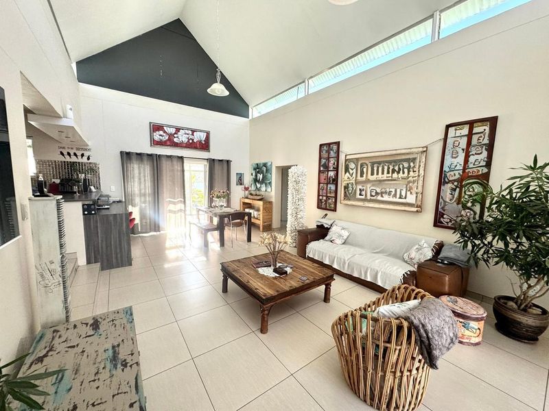 Spacious open-plan living area featuring a high vaulted ceiling, clerestory windows for natural light, and neutral tiled flooring throughout.