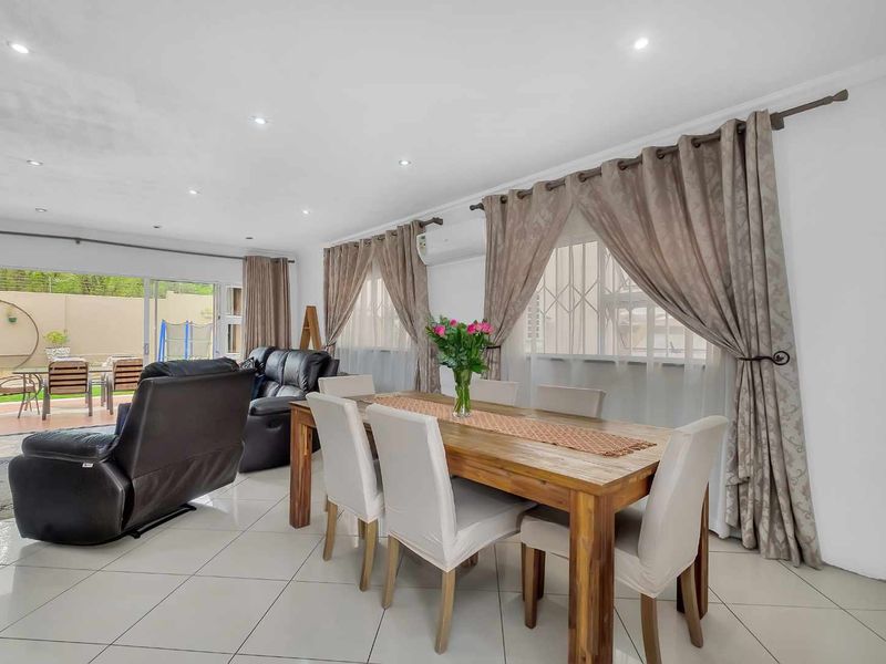 Spacious open-plan living and dining area featuring tiled floors, recessed lighting, and large sliding doors providing seamless access to the outdoor patio.