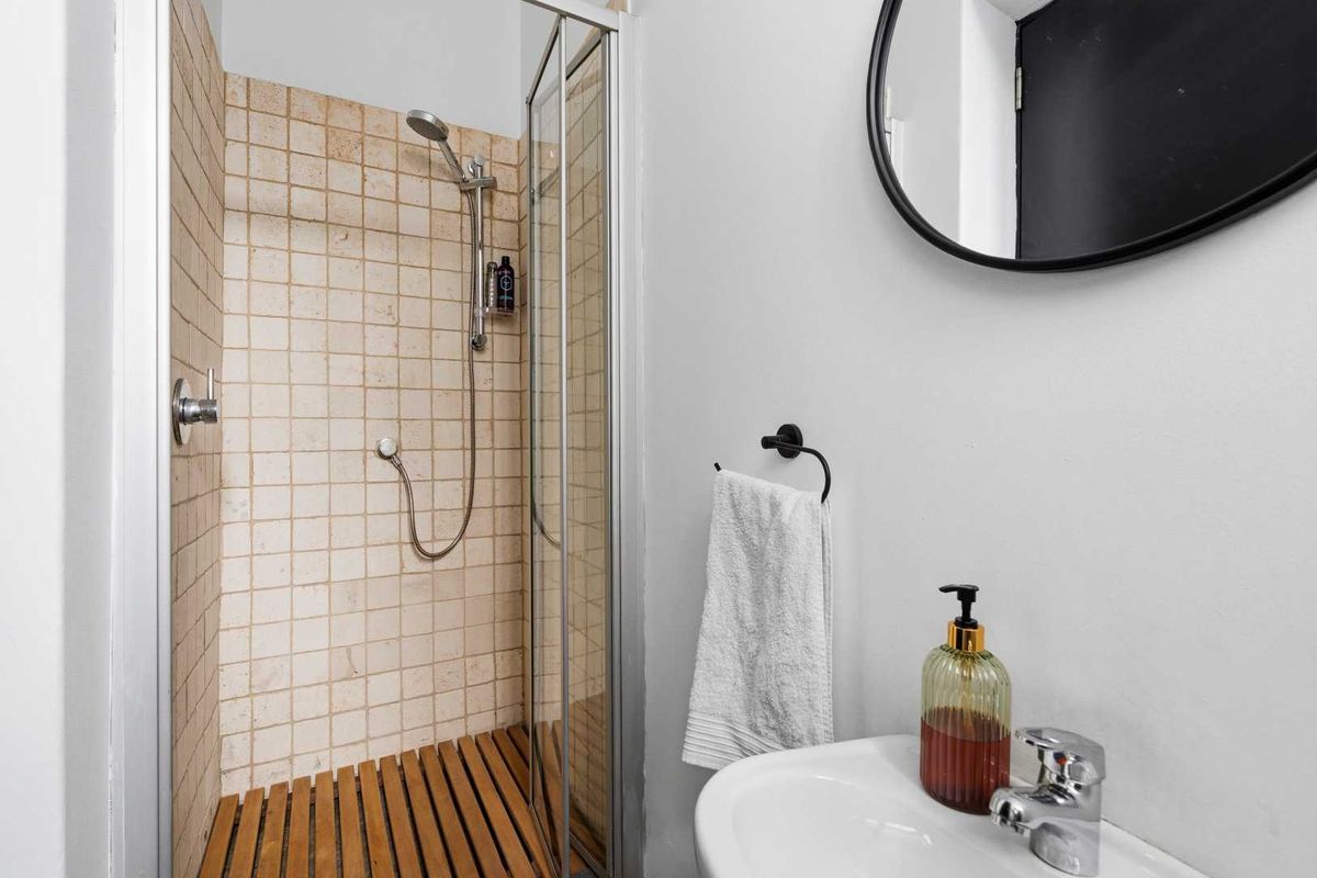 A clean and functional bathroom featuring a glass-enclosed shower with tiled walls and a pedestal basin with modern fixtures.