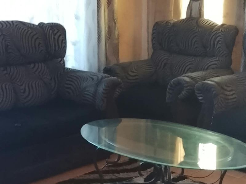 A living room area featuring tiled flooring and window treatments.