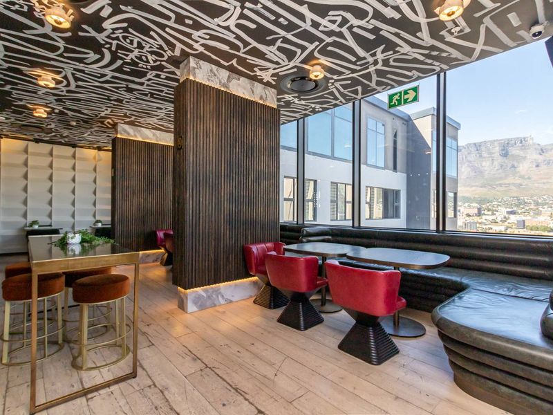 Modern open-plan lounge area featuring floor-to-ceiling windows with mountain views, decorative ceiling art, and integrated timber-slat wall paneling.