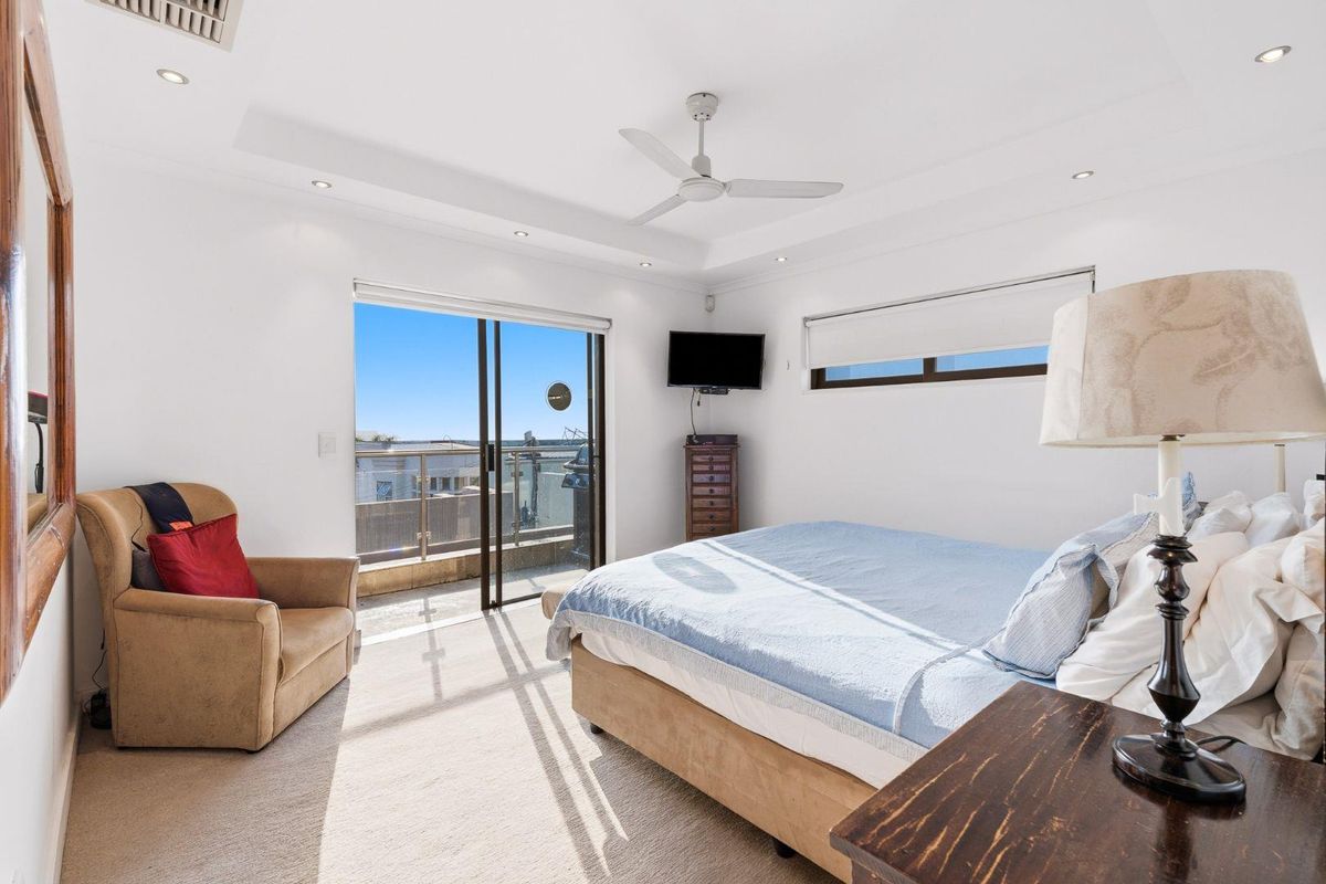 Bright bedroom featuring a tray ceiling, recessed lighting, ceiling fan, and sliding glass doors opening onto a private balcony.