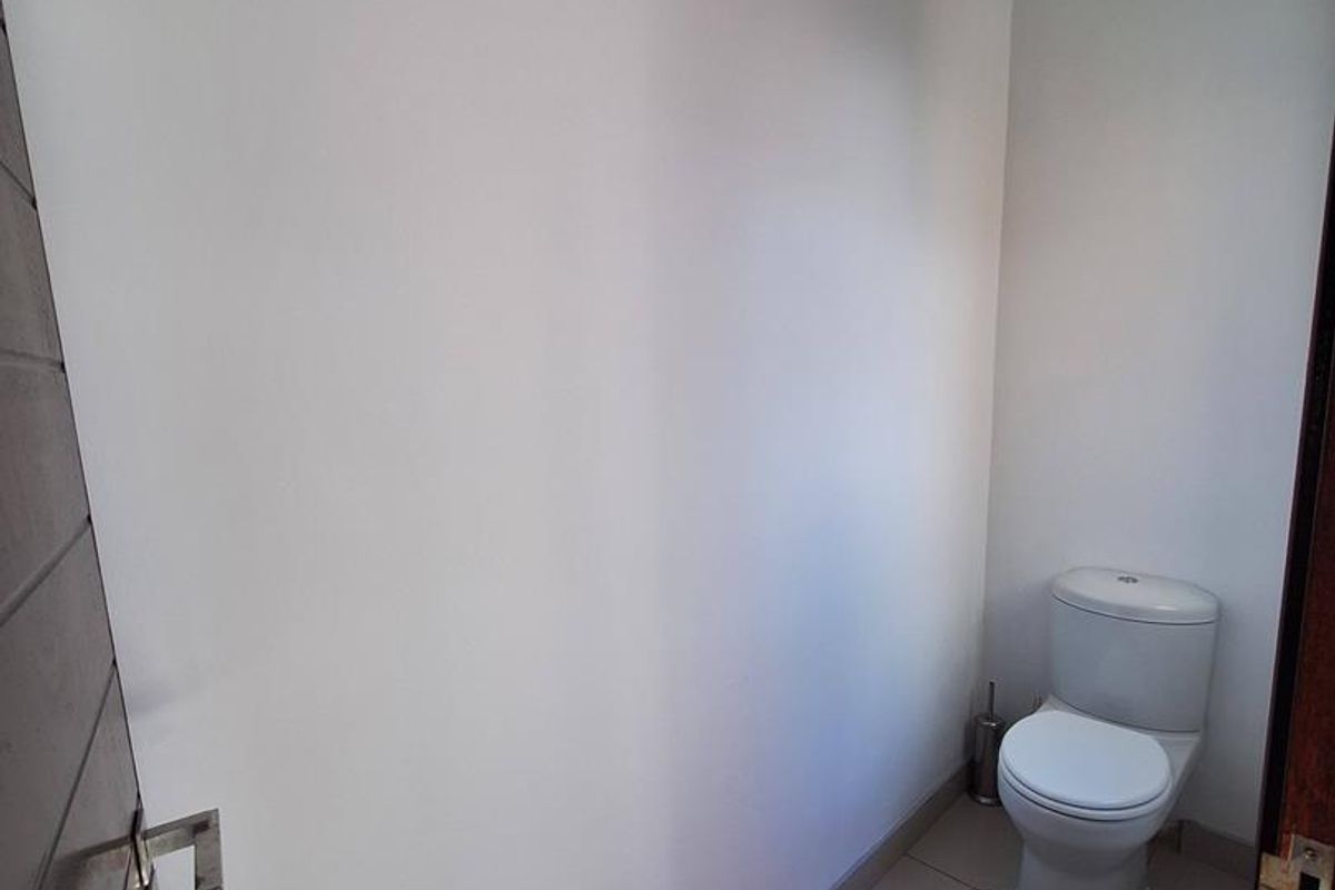 A compact guest bathroom featuring tiled flooring and a standard white toilet suite.