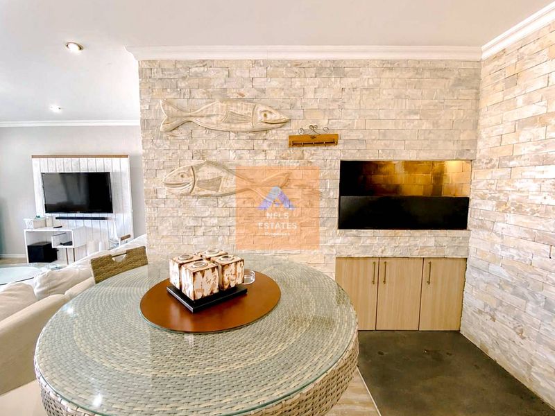 Living area featuring a prominent stone-clad feature wall with a built-in fireplace and integrated storage cabinetry.