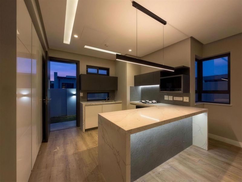 Modern kitchen featuring a stone-topped island, sleek built-in cabinetry, integrated appliances, and sophisticated recessed and pendant lighting in a contemporary open-plan layout.