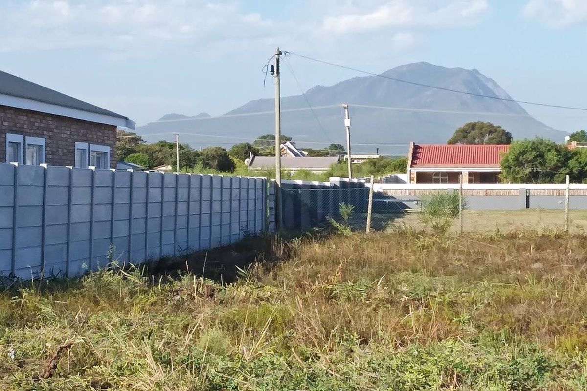 A vacant residential plot featuring perimeter precast concrete walling and views of the surrounding mountain landscape.