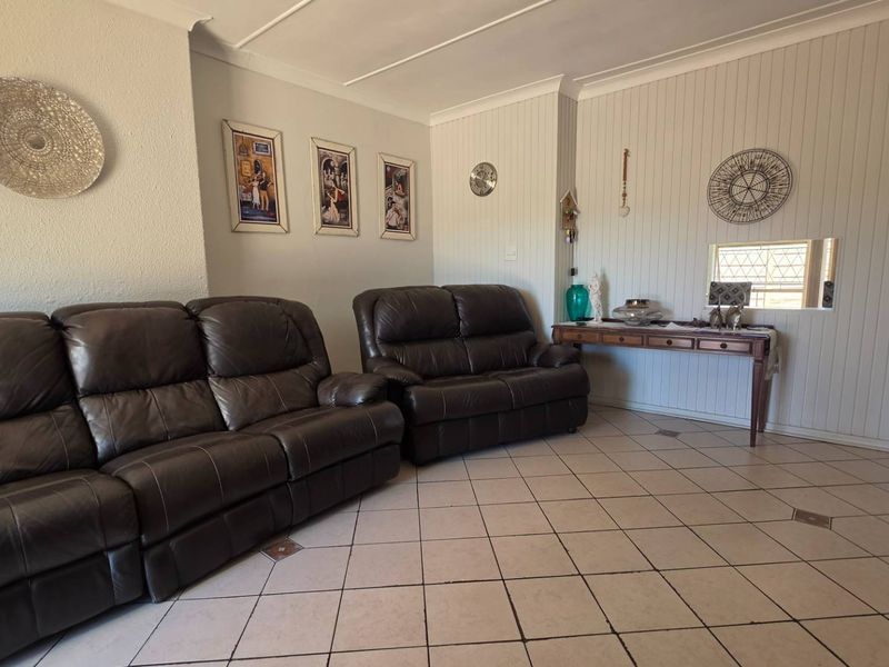 A living room featuring ceramic tile flooring, vertical wood paneling, and a coved ceiling, offering a functional and well-maintained living space.
