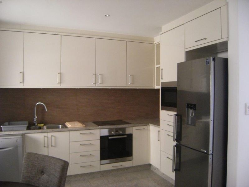 Modern kitchen featuring neutral cabinetry, integrated appliances including an oven and microwave, and a tiled backsplash.