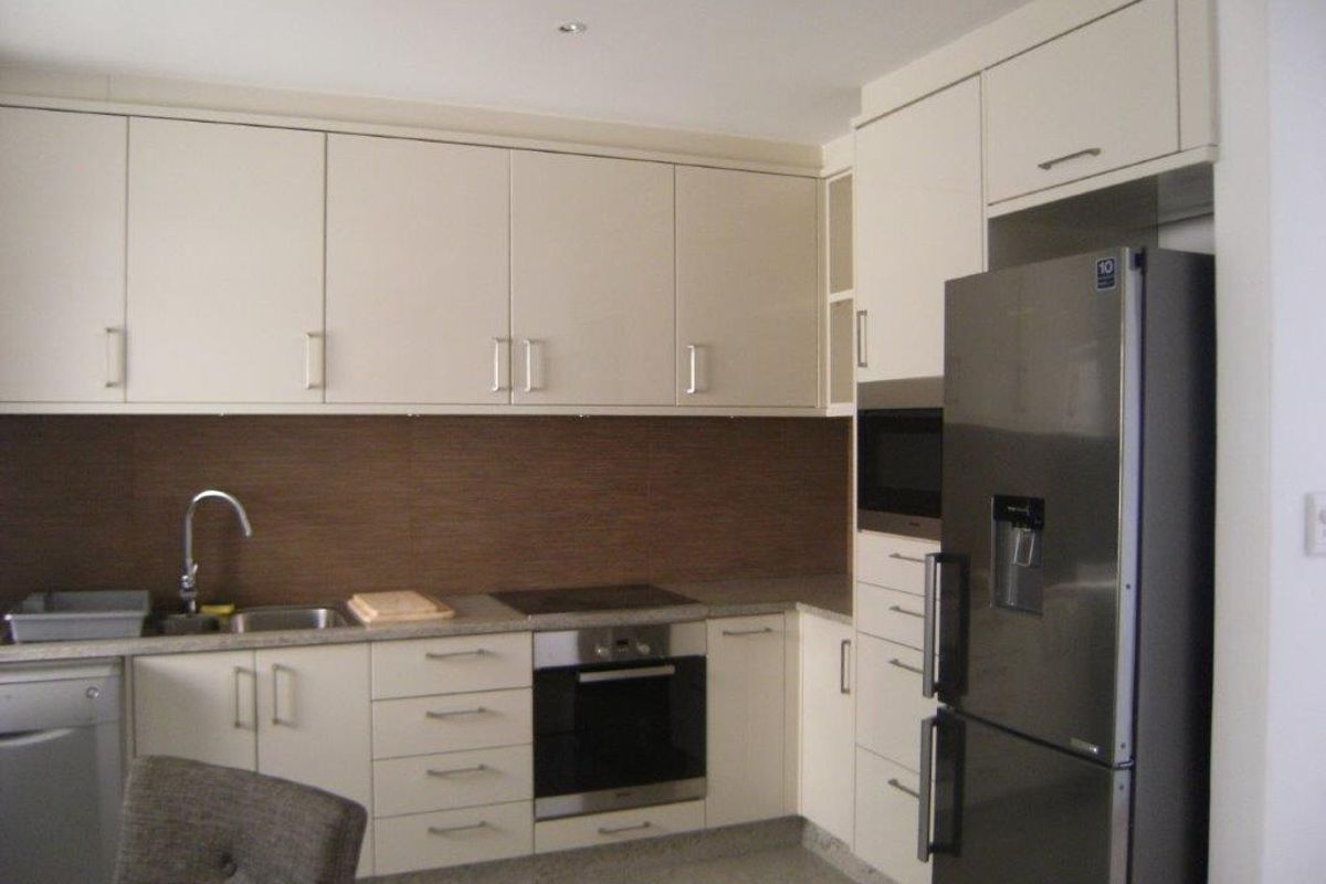 Modern kitchen featuring neutral cabinetry, integrated appliances including an oven and microwave, and a tiled backsplash.