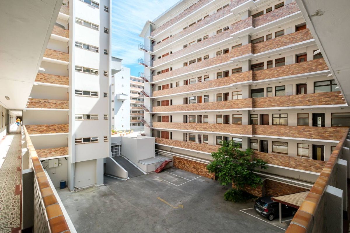 An elevated view of the apartment complex courtyard, featuring multi-story brick facades, paved parking area, and external staircases.