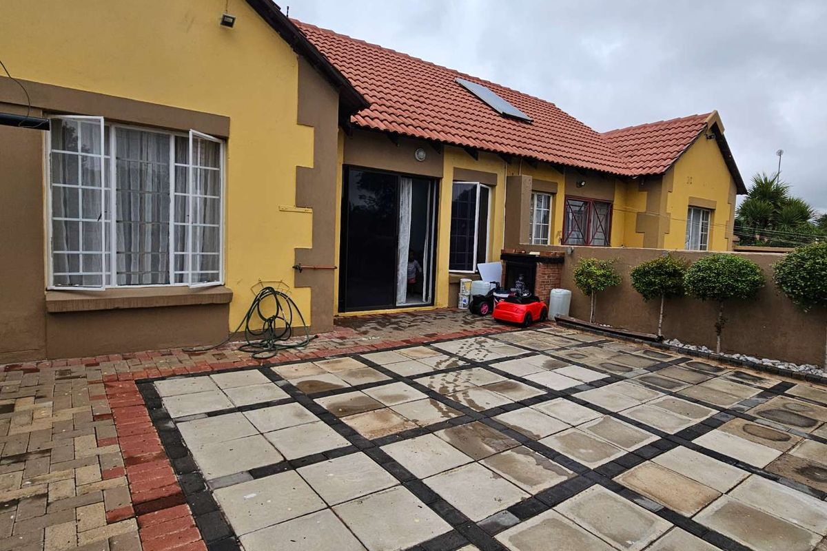 Rear exterior view of the townhouse featuring a paved patio area, sliding door access, and a tiled roof with a solar water heater.