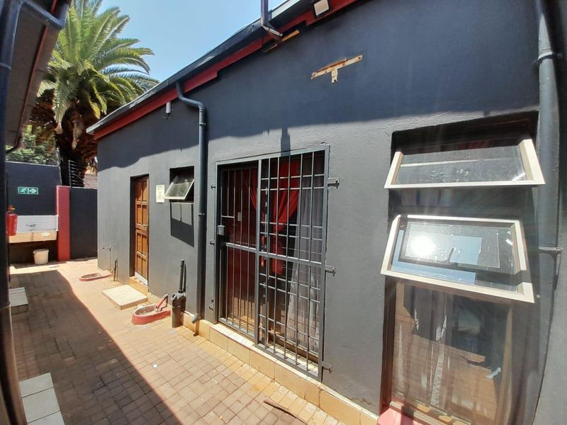 Rear exterior view of the property featuring dark painted walls, security gates, and paved walkway access.