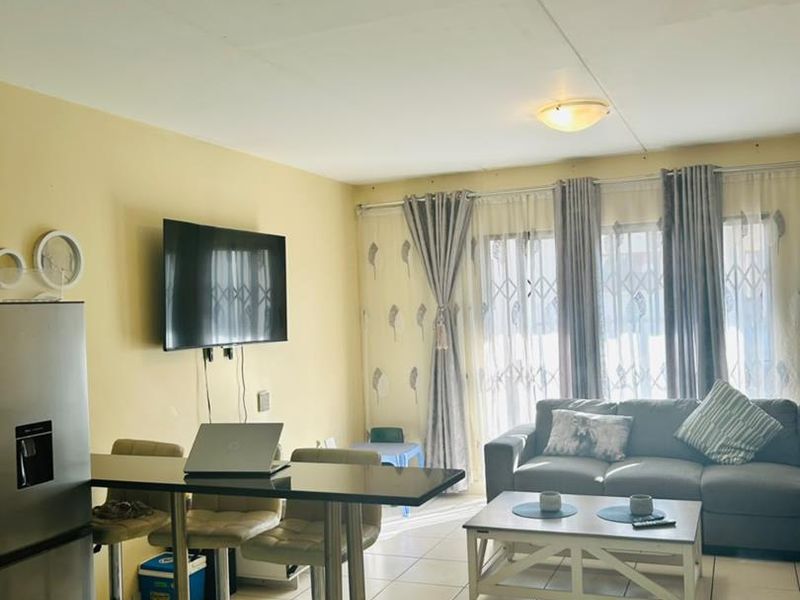 Open plan living area featuring tiled flooring and access to a balcony through a security gate.