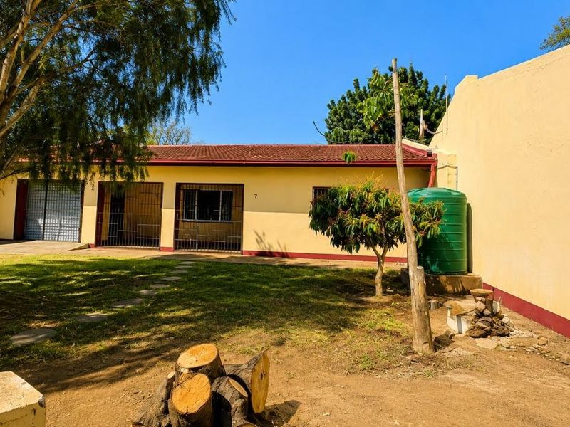 Rear exterior view of the townhouse featuring a garden area, security gates, and a water storage tank against a boundary wall.