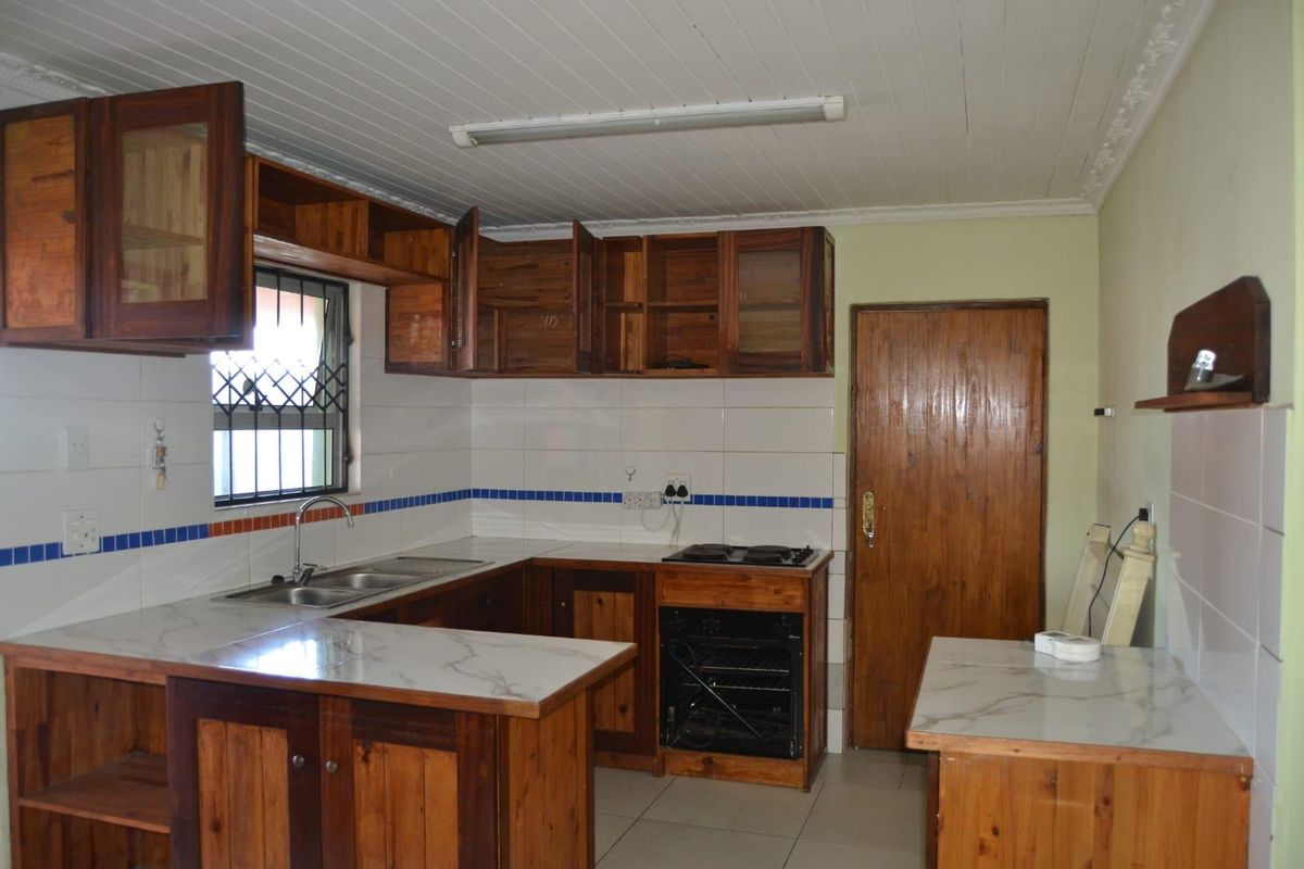 Functional kitchen featuring wooden cabinetry, marble-look countertops, a built-in oven and hob, and a double sink with tiled splashback.