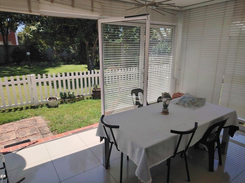 A covered patio area featuring tiled flooring and large sliding glass doors that open directly onto a private garden space.