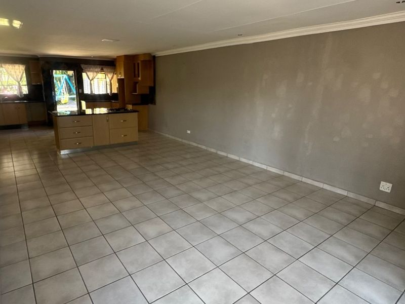 Spacious open-plan living and kitchen area featuring tiled flooring, a central kitchen island with built-in cabinetry, and recessed lighting throughout.