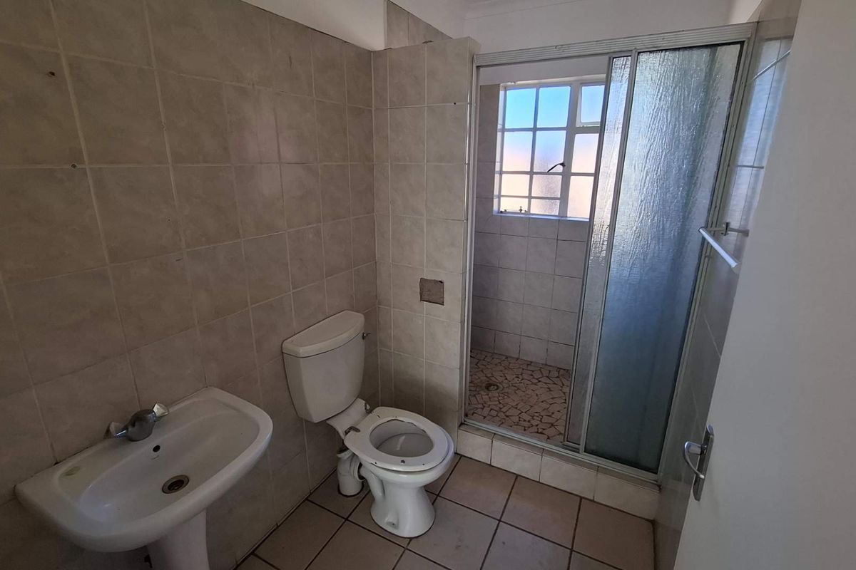 A functional bathroom featuring a pedestal basin, a standard toilet, and a separate shower enclosure with a sliding glass door.