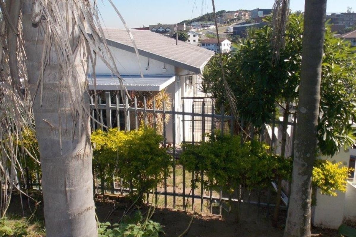 A view of the rear exterior of the house, featuring metal security fencing, a tiled roof, and an external air conditioning unit.