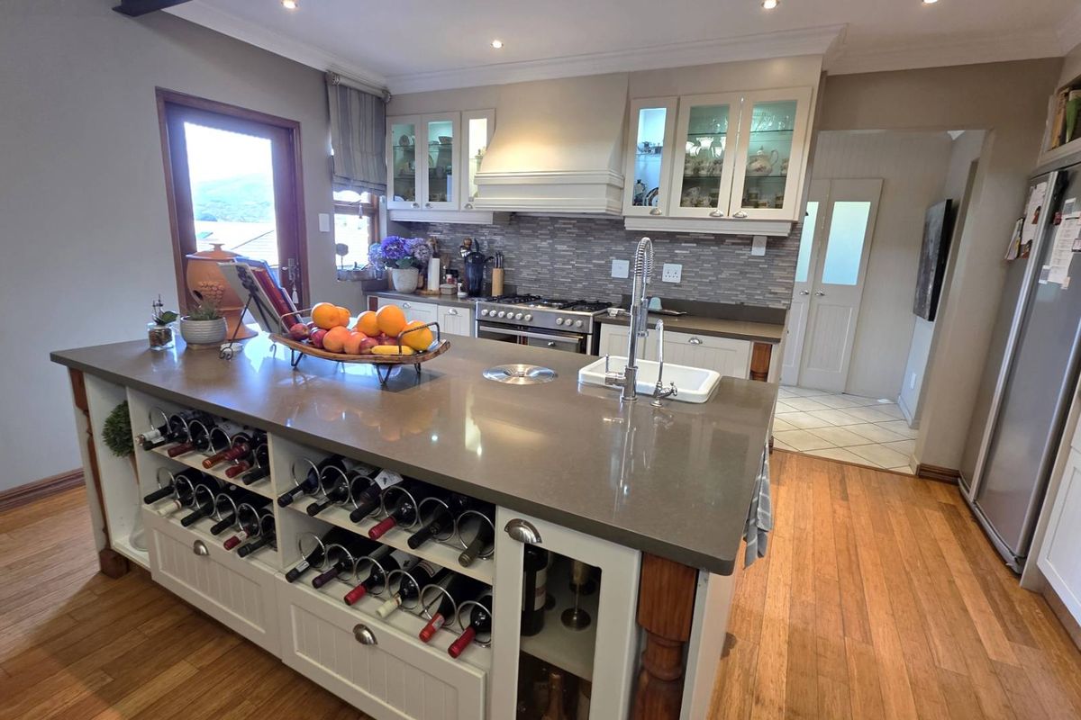 A well-appointed kitchen featuring a large central island with built-in wine storage, stone countertops, gas stove, and elegant glass-front cabinetry.