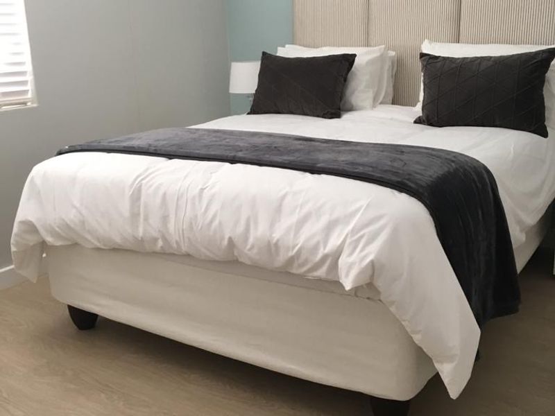 A well-maintained bedroom featuring light-toned laminate flooring and neutral wall finishes, providing a clean and comfortable living space.