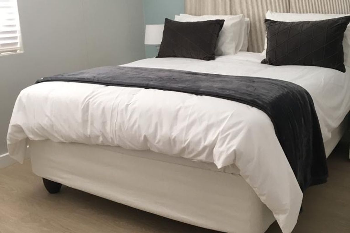A well-maintained bedroom featuring light-toned laminate flooring and neutral wall finishes, providing a clean and comfortable living space.