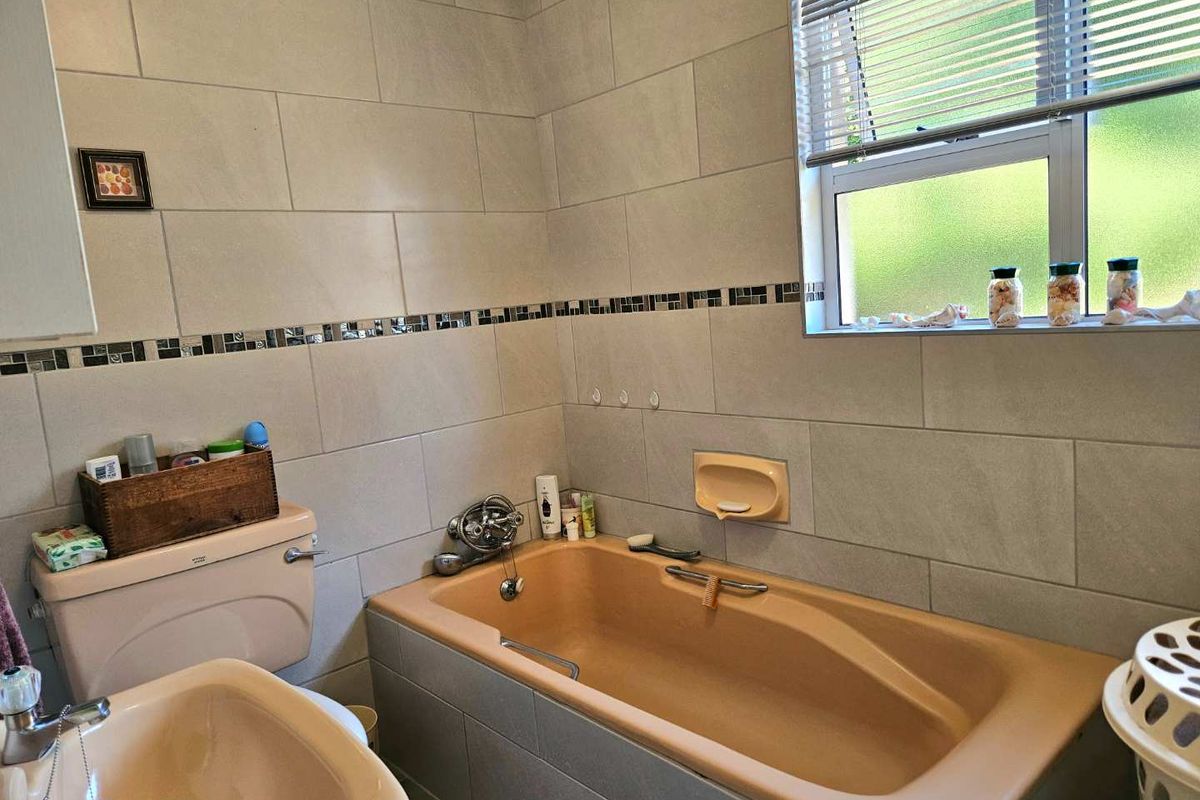 A functional bathroom featuring a neutral tiled finish, a built-in bathtub, and a matching vanity basin with integrated plumbing fixtures.