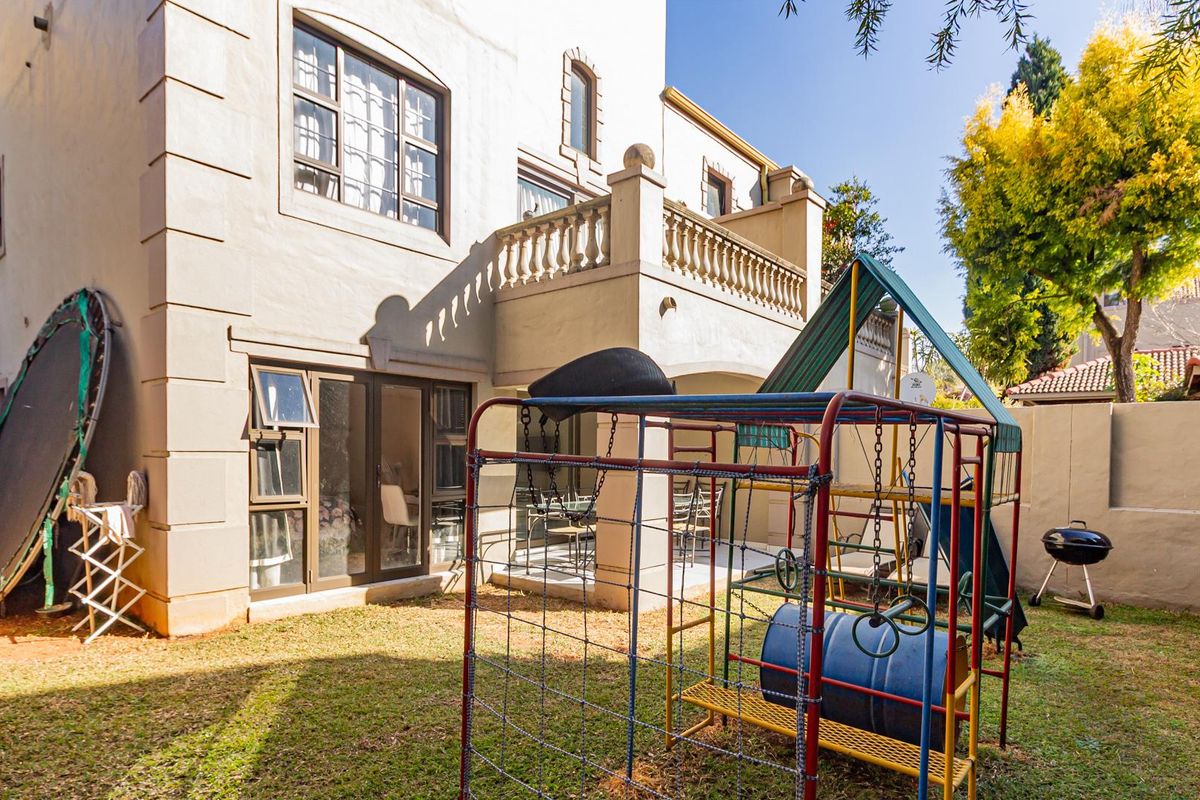 Rear view of the apartment building featuring a paved patio area, a balcony with a stone balustrade, and access via sliding doors.