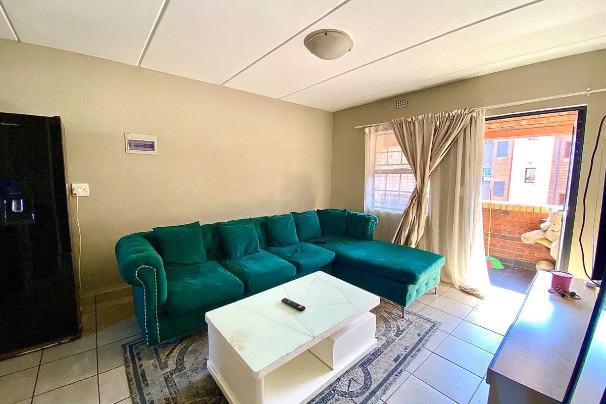 A living room featuring tiled flooring and direct access to a private balcony through a sliding glass door.