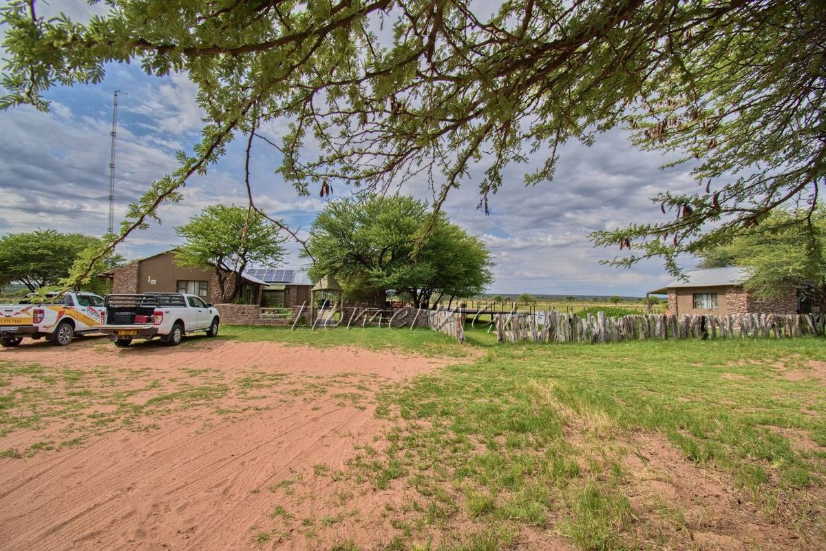 A wide view of the farm property featuring multiple buildings, solar panels, a rustic wooden fence, and expansive outdoor grounds.