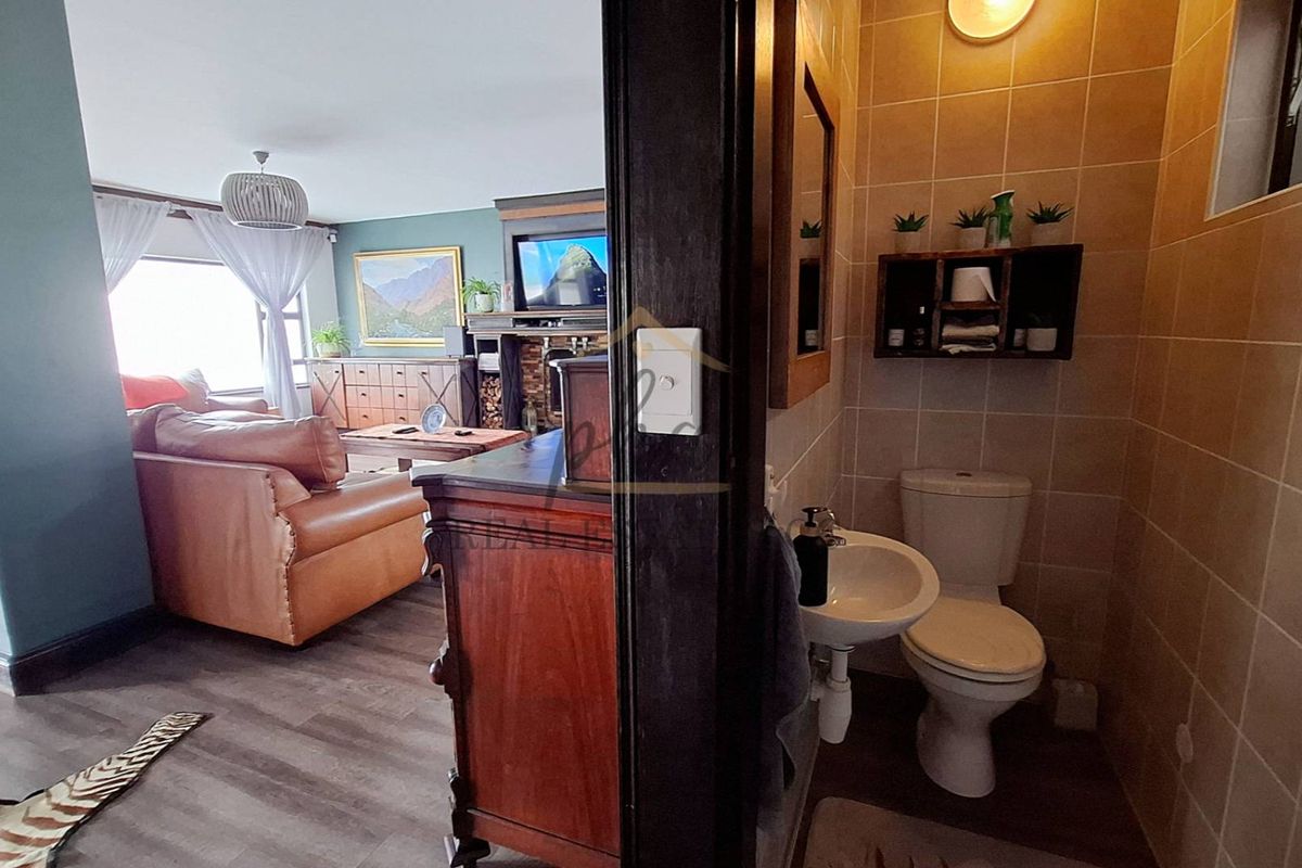 A compact bathroom featuring tiled walls, a wall-mounted basin, and a toilet, conveniently located adjacent to the main living area.