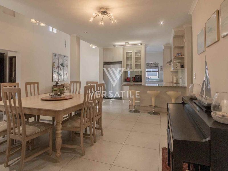 Open plan dining and kitchen area featuring tiled flooring, neutral cabinetry, stone countertops, and recessed lighting in a well-maintained townhouse setting.