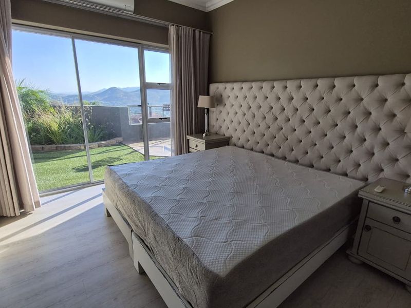 Spacious bedroom featuring laminate flooring, built-in cupboards, and large sliding glass doors opening to a private patio with scenic mountain views.