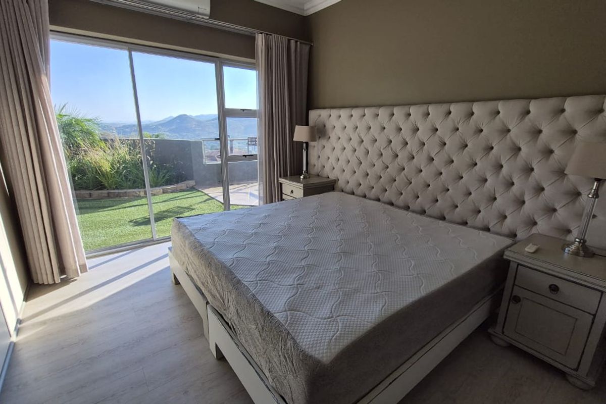 Spacious bedroom featuring laminate flooring, built-in cupboards, and large sliding glass doors opening to a private patio with scenic mountain views.