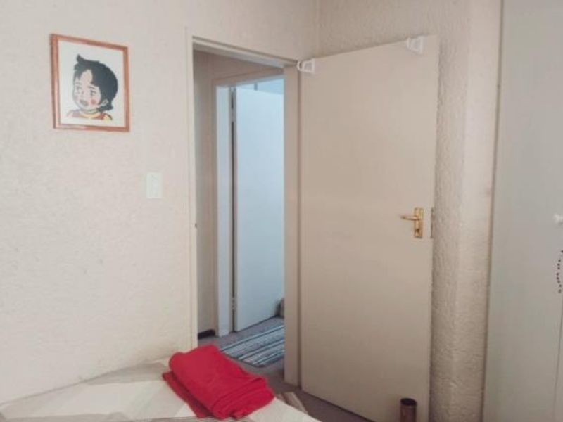 A bedroom interior featuring textured wall finishes and a built-in wardrobe, with a doorway leading to an adjacent hallway.