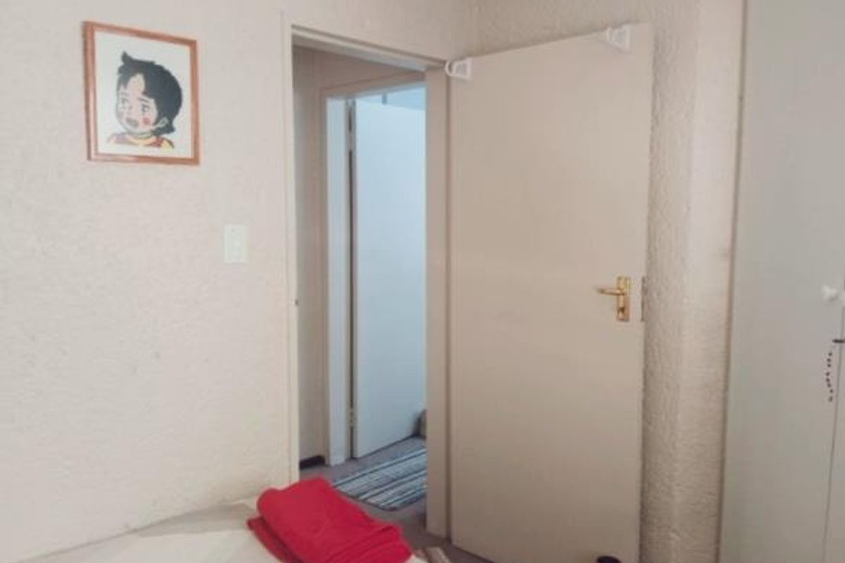 A bedroom interior featuring textured wall finishes and a built-in wardrobe, with a doorway leading to an adjacent hallway.
